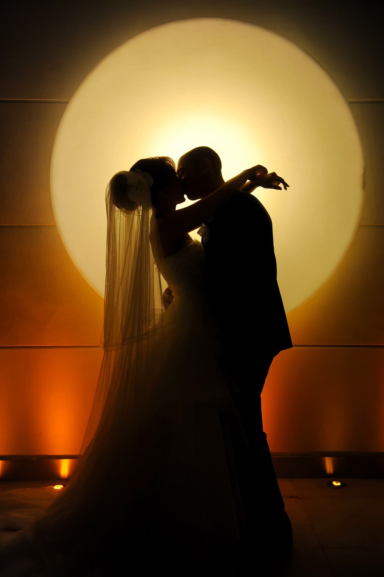 Wedding couple silhouetted against a glowing circular light